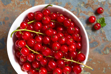Raw red currants (lat. Ribes rubrum) in bowl, photographed overhead on slate with natural light (Selective Focus, Focus on the top of the red currants in the bowl)