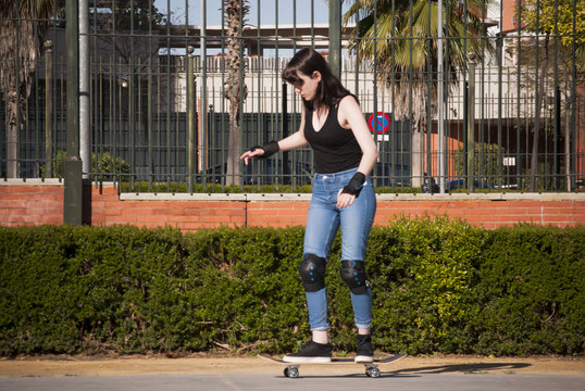 Beautiful young woman practicing with the skateboard on the stre