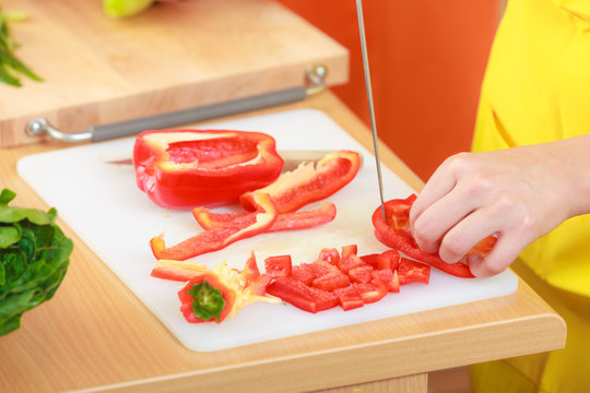 Woman preparing vegetables salad slicing red pepper