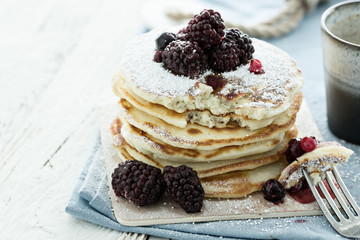 Delicious pancakes with berries on white wooden background