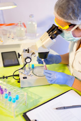 Fototapeta premium Woman in a laboratory working with a microscope, selective focus
