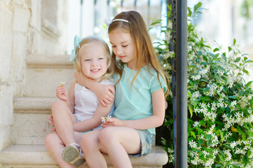 Fototapeta premium Two adorable little sisters laughing and hugging each other