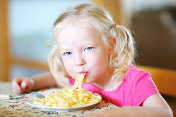 Cute funny little girl eating spaghetti