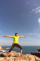 young man doing yoga exercises on the beach.