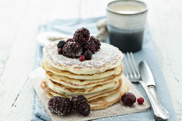 Delicious pancakes with berries on white wooden background