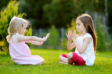 Two cute little sisters having fun together on the grass