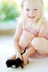 Obraz premium Adorable little girl playing with small kitten