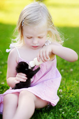 Adorable little girl feeding small kitten with kitten milk from the bottle © MNStudio