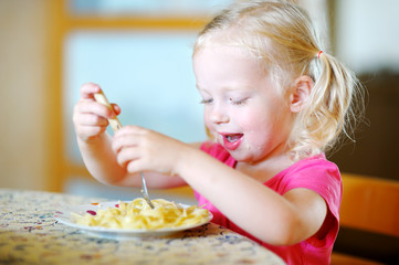 Cute funny little girl eating spaghetti