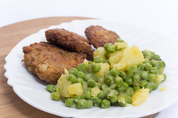 Homemade burgers served with potatoes and green peas