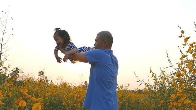 HTML5 Video is required for viewing the videoFather playing with girl daughter against sunset at flower field. Slow motion.

