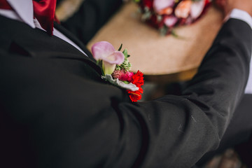 hands of bride and groom with wedding ring on wooden table with bouquet of roses