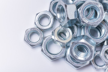 Macro image of pile of grey metal nuts over white background