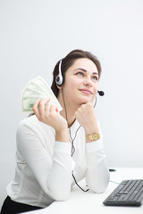 dreamy girl in headphones in the workplace with money in hand