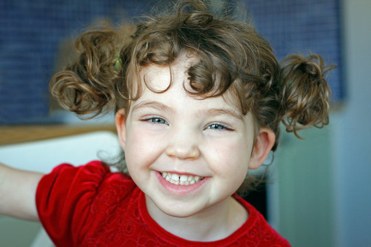 Portrait of adorable young cute girl with hair tufts, laughing and smiling.