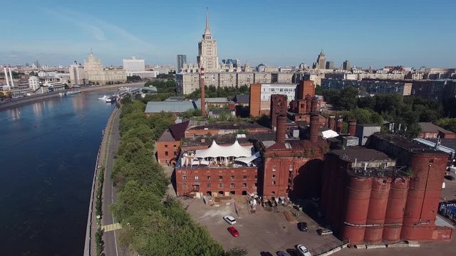 Quadrocopter shoot summer restaurant on roof of brick building in center of Moscow city in summer cloudless day. Building of Radisson Hotel