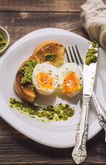 Soft-boiled egg with toasted bread and pesto sauce