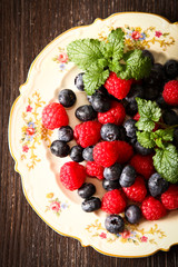 blueberries and raspberries on a plate ventazhnoy dark wood back