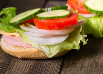 Sandwich with salad and other vegetables on old gray boards