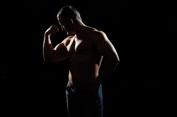 Muscular male posing on black background