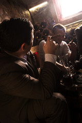 Three businessmen sitting in the wine cellar drinking wine and smoke cigar, resting after a hard day at work.