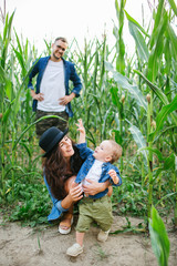 Young hipster family with cute baby in cornfield smiling
