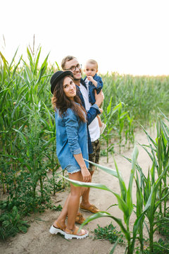 Young hipster father mother holding cute baby in corn field