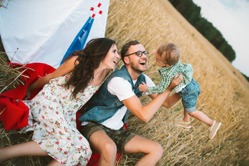 Young hipster father, mother cute baby son on picnic