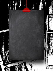 Close-up of one blank blackboard frame hanged by red clip against black and white splotchy ink background