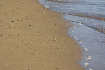 Morning beach with tidal bore and smooth sand with scattering of little stones