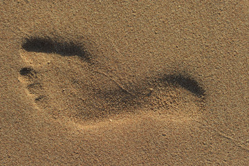 Fototapeta na wymiar Man's footprint on a sand close-up