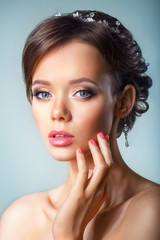 portrait of the beautiful young girl in an image of the bride with ornament in hair.Beautiful Spa Woman Touching her Face. Youth and Skin Care Concept.