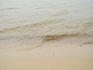 kleine Wasserwellen am sandigen Flussufer im Sonnenlicht

