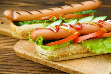 Spicy hotdog with fresh vegetables lying on wooden kitchen board