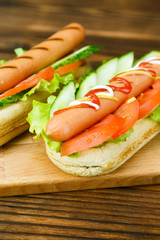 Spicy hotdog with fresh vegetables lying on wooden kitchen board