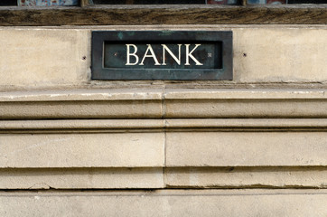 Bank sign painted on letterbox in wall. White word Bank painted on metal letterbox or deposit box in a stone wall in Bath, Somerset, UK