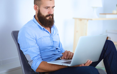 Handsome young man sitting and working on laptop computer