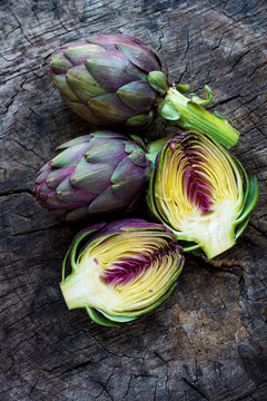 Organic Artichokes on  rustic wooden board