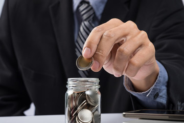 Hand putting mix coins and seed in clear bottle and copyspace, B