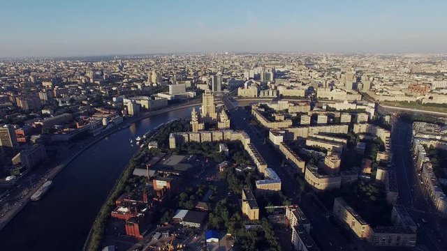 Quadrocopter fly highly over Moscow city in summer sunny day. Modern and old edifices. Building of Radisson Royal Hotel. Moscow river