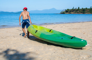 Man pulls a kayak to shore beach