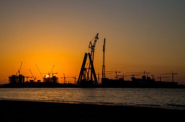 Fototapeta na wymiar oil tower in sunset silhouettes orange sky