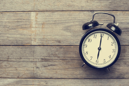 Retro alarm clock on wooden table, vintage style