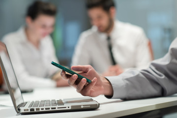 Fototapeta premium close up of businessman hands using smart phone on meeting