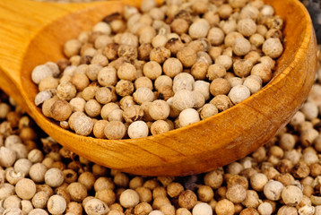 close up white pepper and wooden spoon as background