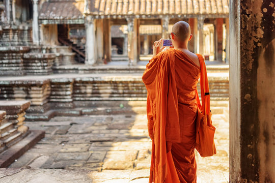 Buddhist monk with smartphone taking picture in Angkor Wat