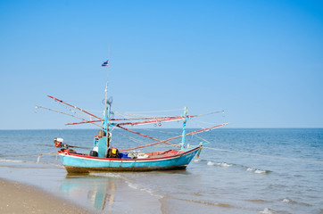 Naklejka na ściany i meble old wooden local fishing boat on on sea coast and beach with sum