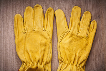 Pair of yellow leather protective gardening gloves on wooden boa