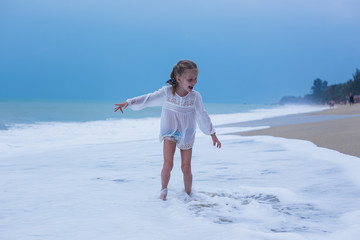 Girl running on the waves in a storm on the coast of the sea