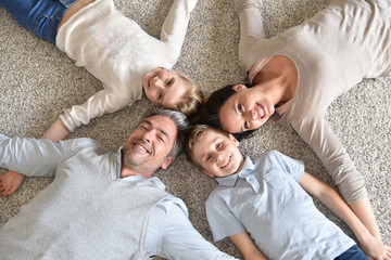 Upper view of family of 4 laying on carpet © goodluz